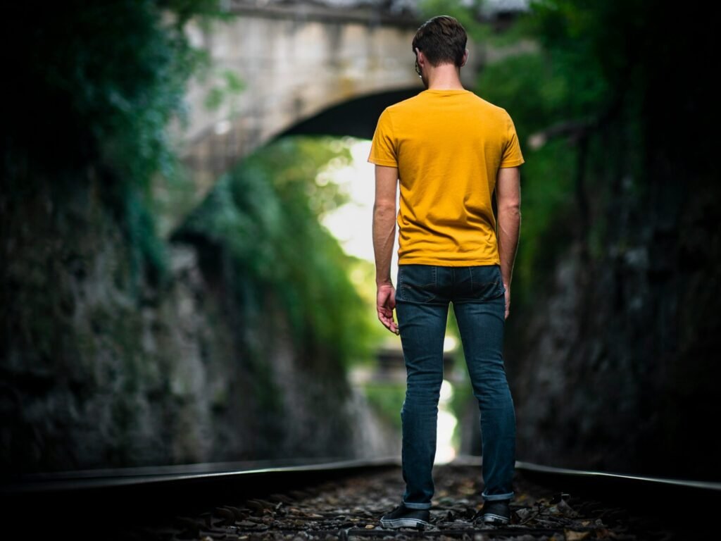 man standing in the middle of train track